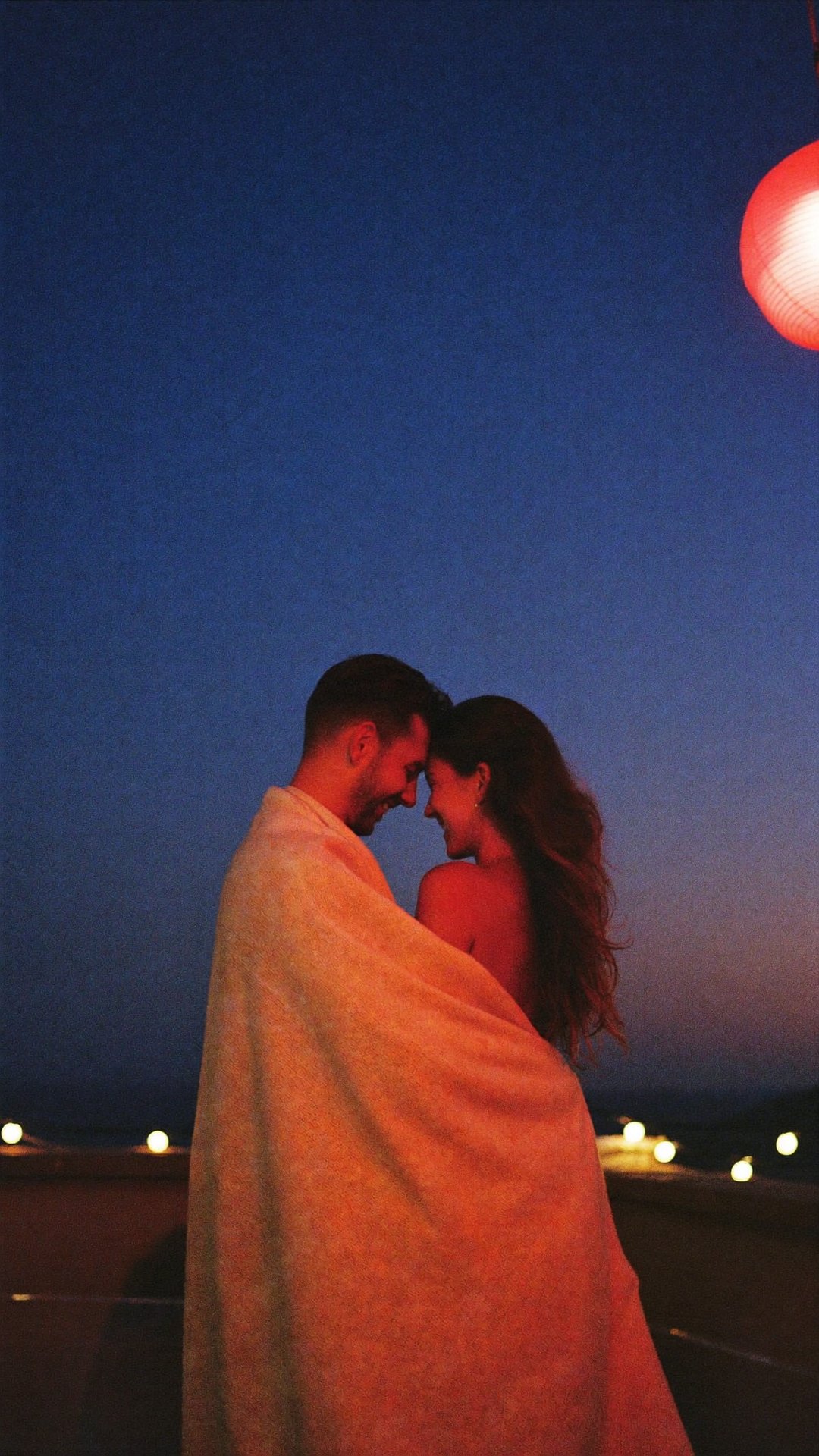 Couple wrapped in a blanket at dusk
